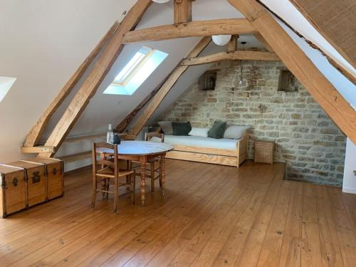 a room with a bed and a table in a attic at Gîte de groupe agritourisme 3 gîtes mitoyens 25 couchages Convivialité et intimité in Lingèvres