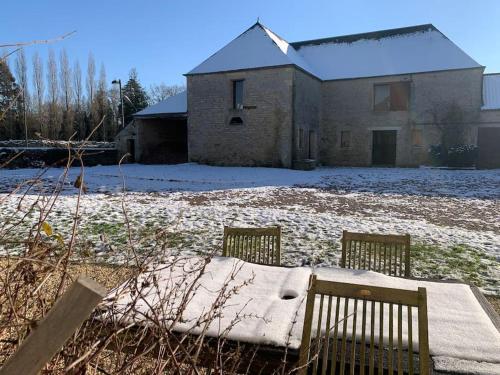 a house with a snow covered yard with two chairs at Gîte de groupe agritourisme 3 gîtes mitoyens 25 couchages Convivialité et intimité in Lingèvres