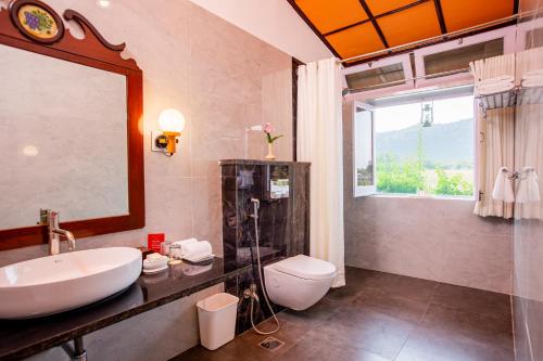 a bathroom with a sink and a toilet and a window at Shikarbadi Hotel - Heritage by HRH Group of Hotels in Udaipur