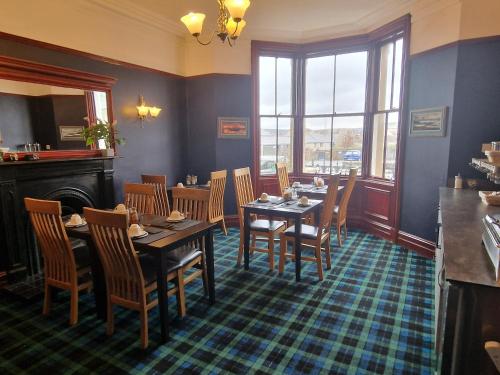 a dining room with tables and chairs and a fireplace at Carradale Guest House in Lerwick