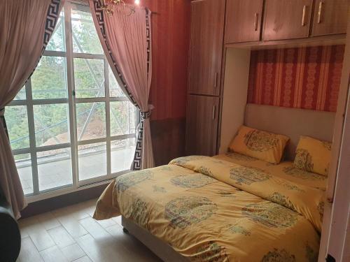 a bedroom with a bed and a large window at Beverly Hills Kuza Gali, Nathiagali District Abbottabad in Abbottabad
