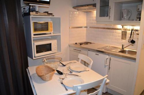 une petite cuisine avec une table et deux chaises ainsi qu'une table blanche dans l'établissement Résidence Caron - Studio pour 2 Personnes 064, aux Menuires