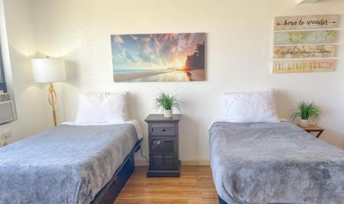 Cette chambre comprend deux lits et un tableau mural. dans l'établissement Bright Waikiki Studio condo, à Honolulu