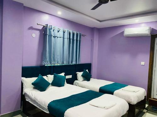 2 Betten in einem Zimmer mit lila Wänden in der Unterkunft Hotel Mangalam in Siddharthanagar