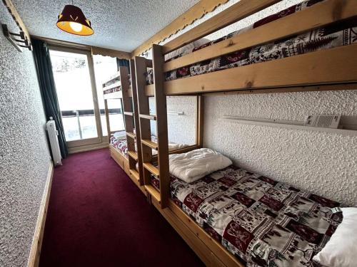 une chambre avec deux lits superposés et une fenêtre dans l'établissement Résidence Pelvoux - Appartement pour 8 personnes exposé Sud et Nord MAE-4434, aux Menuires