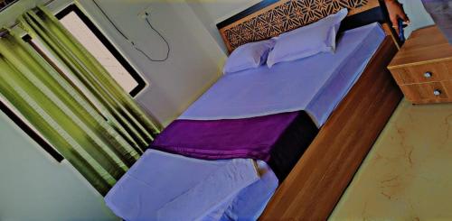 uma cama com lençóis e almofadas roxos num quarto em Glamour Palace em Gaya