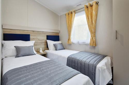 英戈爾德梅爾斯的住宿－Ingoldale Holiday Park，一间卧室设有两张床和窗户。
