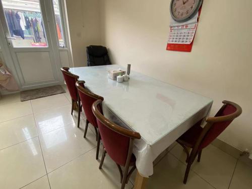 a white table with chairs and a clock on the wall at London Homestay with big double room in London