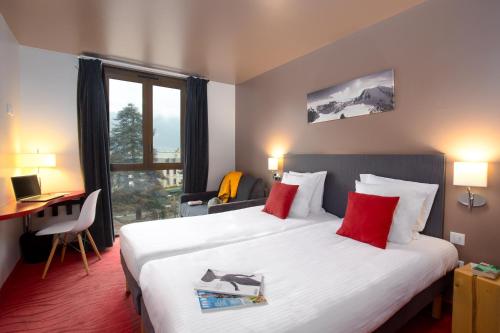 una camera d'albergo con un grande letto con cuscini rossi di SOWELL HOTELS Le Parc & Spa a Briançon