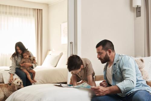 a man reading a book to a child in a hotel room at Novotel Athens in Athens