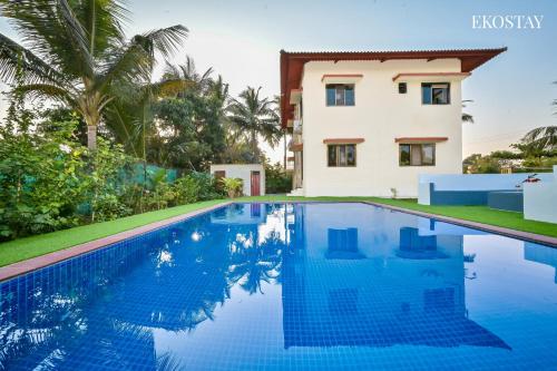 a villa with a swimming pool in front of a house at EKOSTAY - Bloomfield Villa in Alibaug