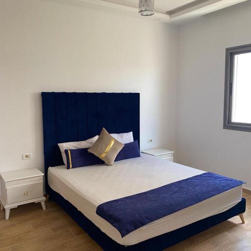 Maison de Noé Djerba Midoun في ميدون: غرفة نوم مع سرير كبير مع اللوح الأمامي الأزرق
