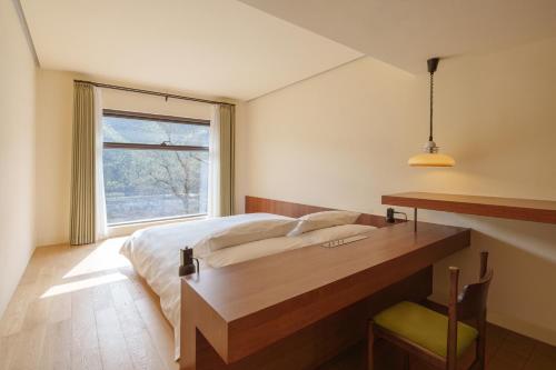 1 dormitorio con cama, escritorio y ventana en Mooke&Co Moganshan, en Deqing