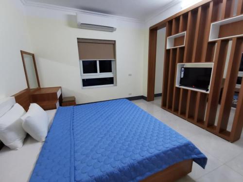 a bedroom with a blue bed and a flat screen tv at Sóng Biển Hotel Cửa Lò in Cửa Lô