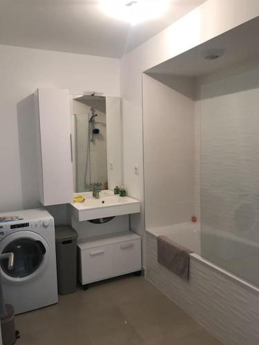 La salle de bains blanche est pourvue d'un lavabo et d'un lave-linge. dans l'établissement Appartement neuf, climatisé, piscine, terrasse, à La Londe-les-Maures