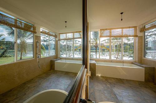La salle de bains est pourvue de 2 lavabos, d'une baignoire et de fenêtres. dans l'établissement Village Paradise, à Beliatta