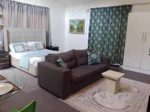 a living room with a couch and a bed at Zenith Guesthouse in Pretoria