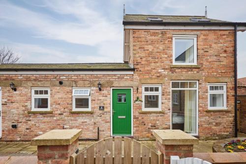 a brick house with a green door and a wooden fence at Host & Stay - Jubilee Close in Hunmanby
