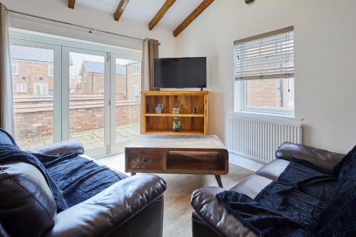 a living room with two couches and a flat screen tv at Host & Stay - Jubilee Close in Hunmanby