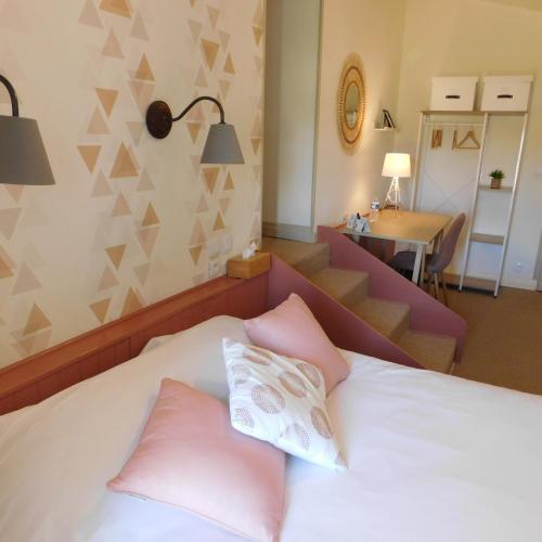 a bedroom with a bed with pink pillows and a staircase at Logis Hotel Le Prince Noir in Sérignac-sur-Garonne