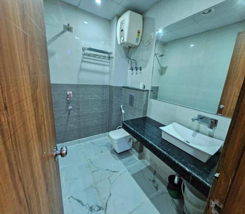 ein Badezimmer mit einem Waschbecken, einem WC und einem Spiegel in der Unterkunft Hotel Casa Suites Near International Airport in Neu-Delhi