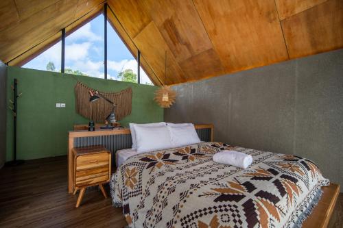 een slaapkamer met een bed en een groot raam bij Black Wood Cabin in Kintamani