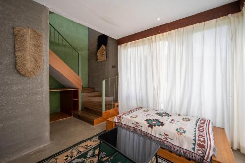 a bedroom with a bed and a window and a staircase at Black Wood Cabin in Kintamani