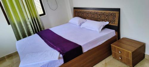 um pequeno quarto com uma cama e uma cabeceira em madeira em Glamour Palace em Bodh Gaya
