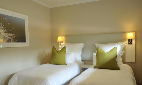 two beds in a hotel room with green pillows at Cresta Sprayview Victoria Falls in Victoria Falls