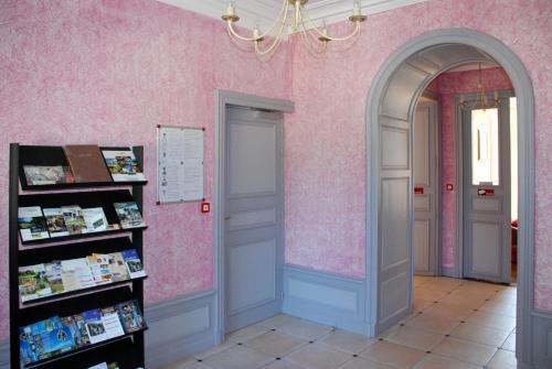 un pasillo con una pared rosa y un estante para libros en Château du Bourg en Saint-Denis-de-Gastines