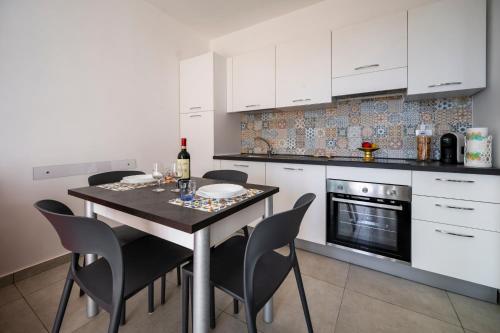 a kitchen with white cabinets and a table with chairs at [Suite Marzamemi] – Near Sea in Marzamemi