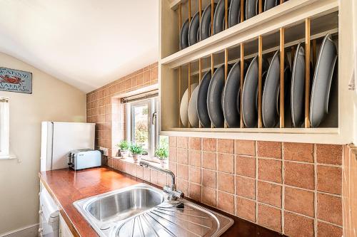 a kitchen with a sink and surfboards on the wall at Cosy cottage in harbourside - Pass The Keys in Cockwood