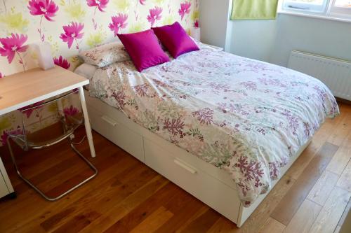 um quarto com uma cama com almofadas roxas e cor-de-rosa em Anna's House em Ickleford
