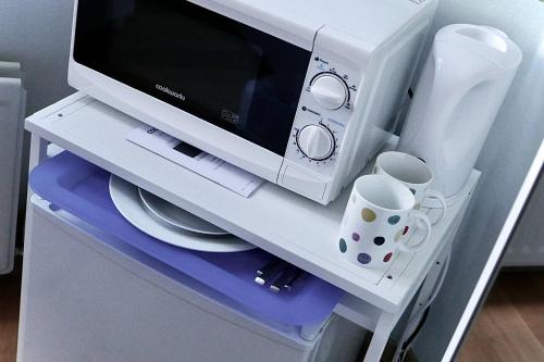 a microwave sitting on top of a refrigerator at Anna's House in Ickleford