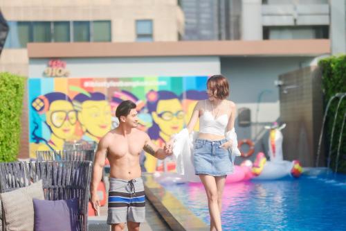 a man and a woman standing next to a pool at ibis Styles Bangkok Silom in Bangkok