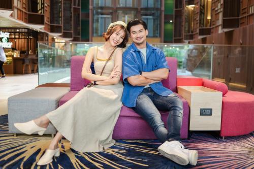 a man and a woman sitting on a pink couch at ibis Styles Bangkok Silom in Bangkok