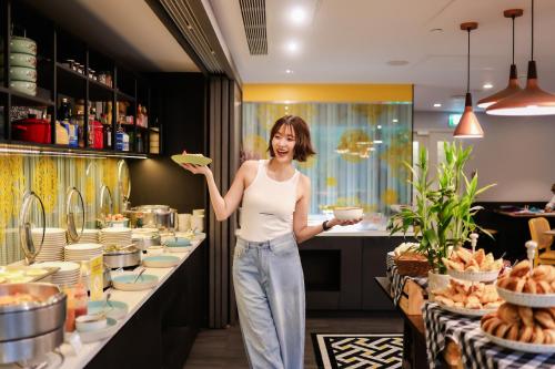 a woman holding a plate of food in a kitchen at ibis Styles Bangkok Silom in Bangkok