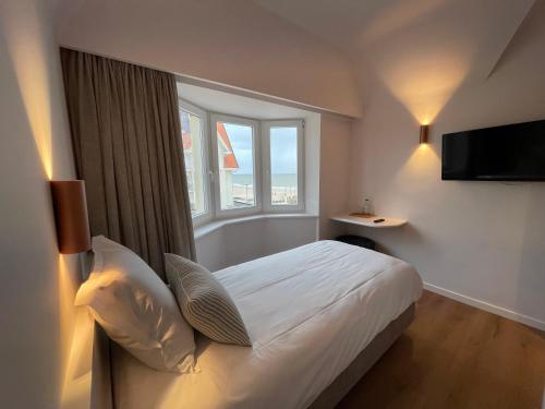 Strandhotel De Haan في دي هان: غرفه فندقيه بسرير ونافذه