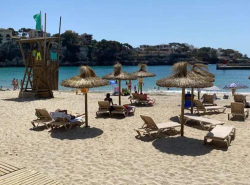 a beach with chairs and umbrellas and people on it at Houpla Porto Cristo in Porto Cristo