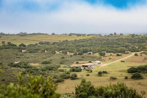 a view of a field with houses on a hill at Baardbos Private Game Reserve in Stilbaai