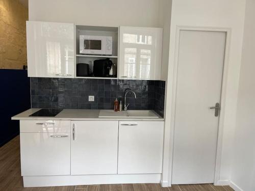 une cuisine blanche avec un évier et un micro-ondes dans l'établissement Appartement climatisé au cœur de Bordeaux, à Bordeaux