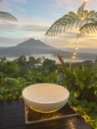 a bowl on a table with a view of a mountain at Black Wood Cabin in Kintamani