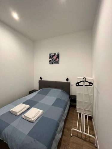 une chambre avec un lit bleu avec deux serviettes dessus dans l'établissement Appartement climatisé au cœur de Bordeaux, à Bordeaux