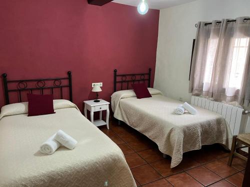 two beds in a room with red walls at EL RIBAZO-Cuenca ciudad in Cuenca