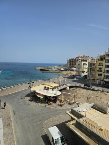 a building on the beach next to the ocean at La Playa Hotel in Marsalforn