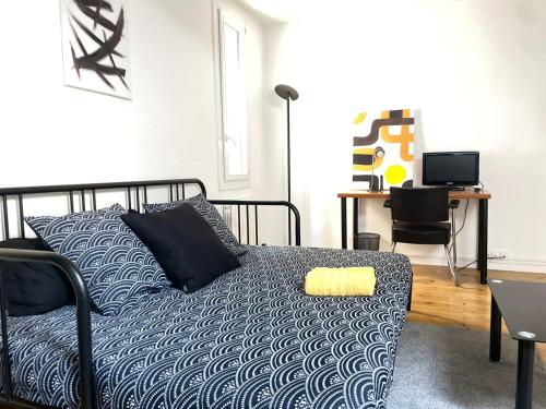 a bedroom with a bed and a desk with a computer at Studio sous les toits in Nîmes