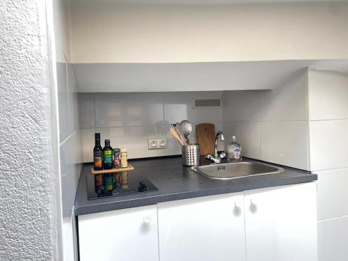 a kitchen with a sink and a counter with bottles at Studio sous les toits in Nîmes