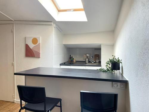 a kitchen with two chairs and a counter top at Studio sous les toits in Nîmes