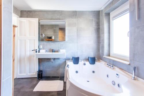 a bathroom with a tub and a sink and a window at Stijlvolle @ luxe vrijstaande woning Maastricht in Eijsden
