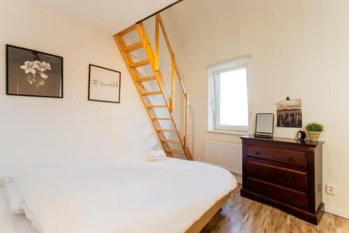 um quarto com uma cama e uma escada ao lado de uma janela em Stijlvolle @ luxe vrijstaande woning Maastricht em Eijsden